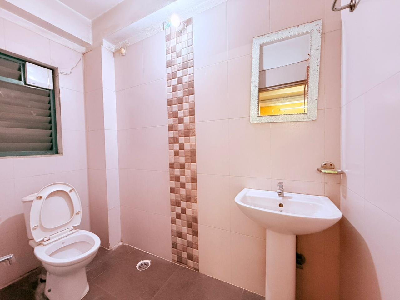 Guest bathroom with pedestal sink, mirror and tiled walls