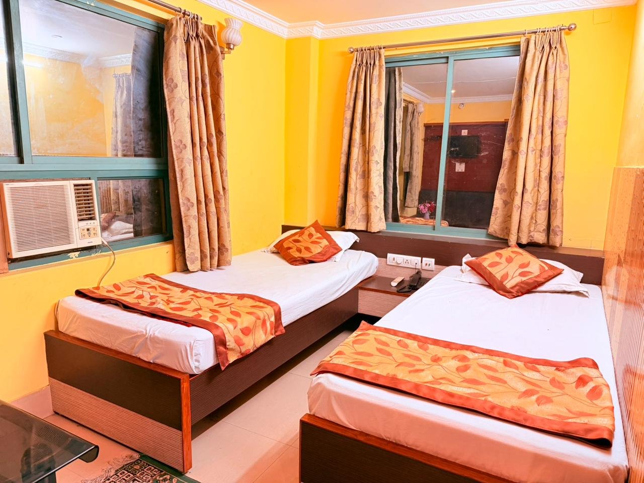 Twin-bed AC room with orange bed runners and cushions