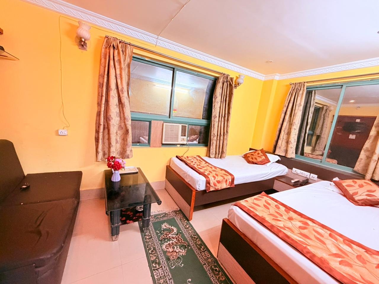 Twin-bed room with sofa, glass table and window air conditioner